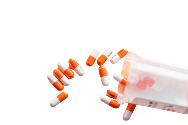Umgekippte Pillendose mit weiß/orangenen Pillen, die auf de Tisch verteilt liegen